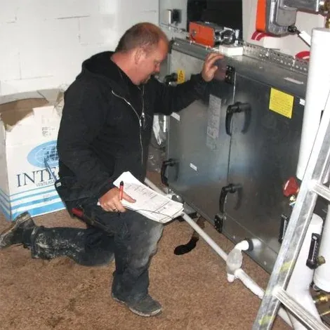 Sotare kontrollerar ett ventilationsaggregat med ett protokoll i handen