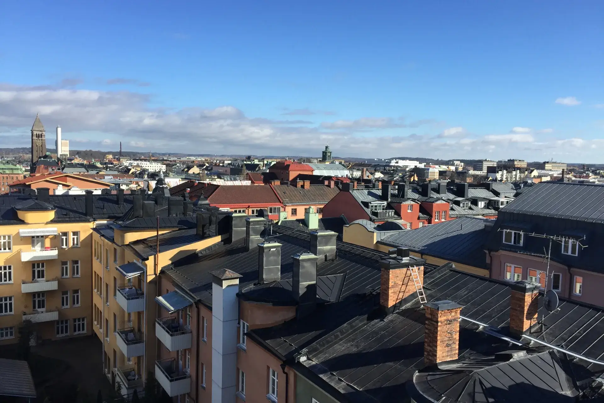 Utsikt över hustak och skorstenar i centrala Norrköping, med rådhustornet i fjärran